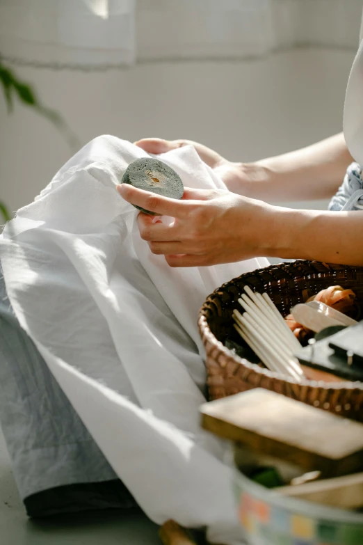 a woman that is sitting down with a basket, pexels contest winner, wearing white silk robe, carved soap, grey, inspect in inventory image