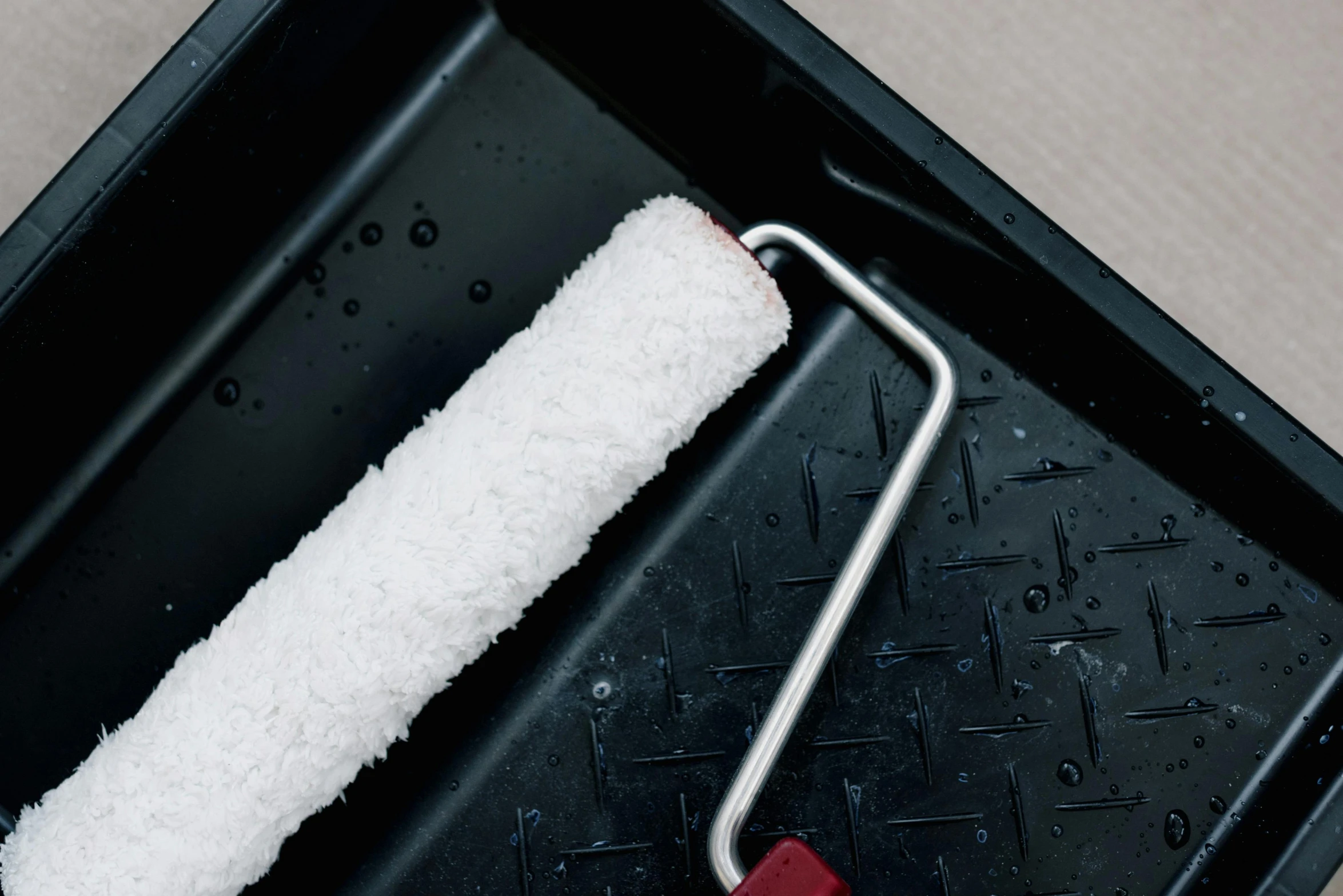 a white paint roller sitting on top of a black tray, by Julia Pishtar, filling with water, square, thumbnail, close angle