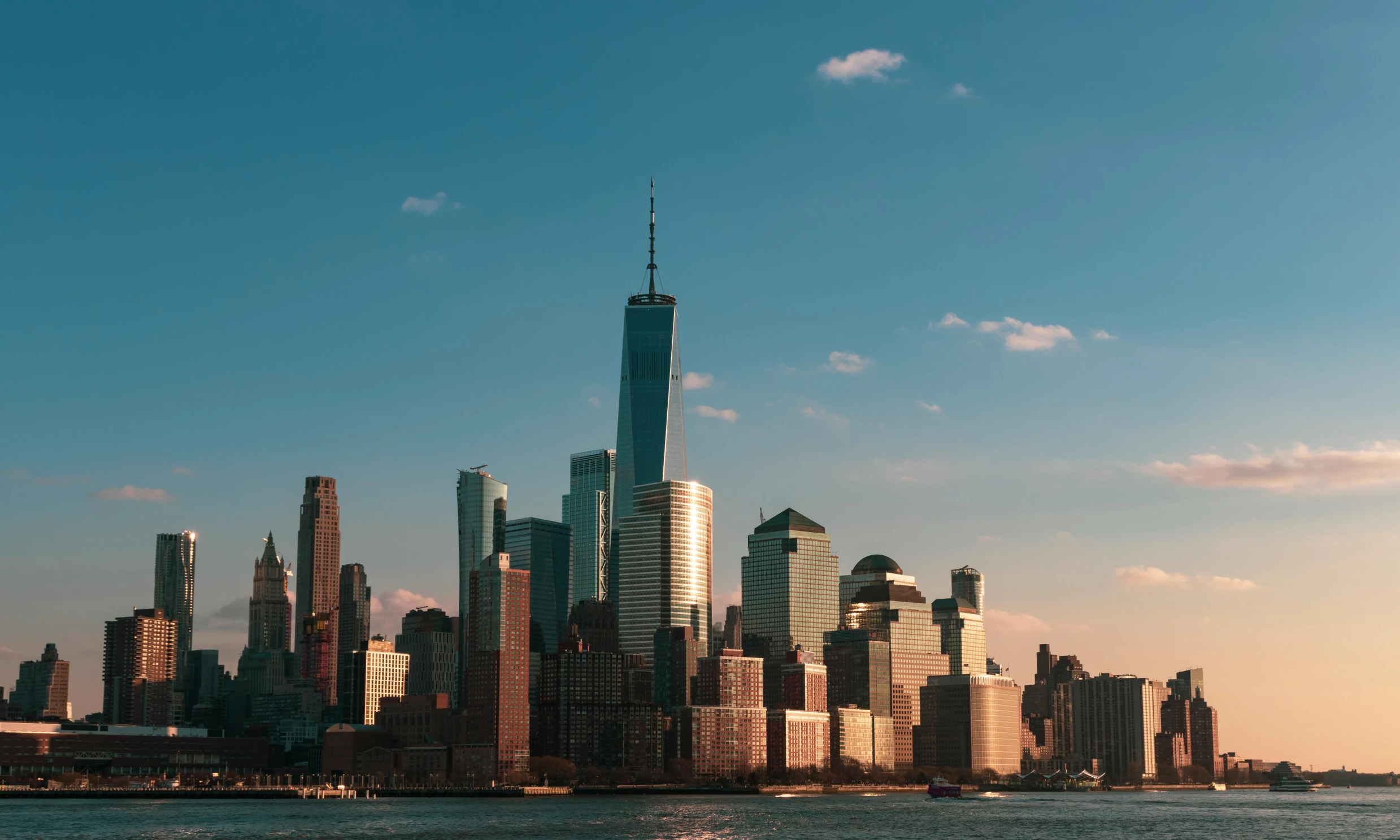 a large body of water with a city in the background, pexels contest winner, new york background, promo image, tall metal towers, nice afternoon lighting