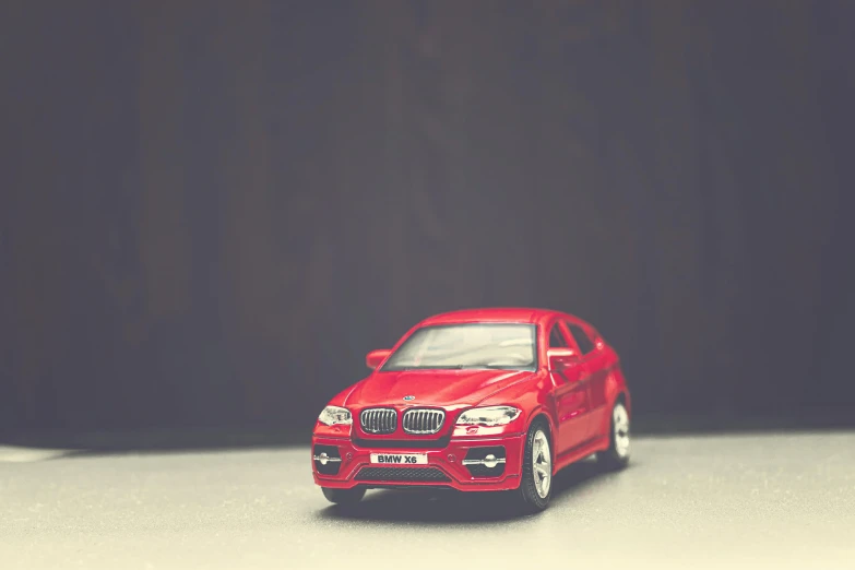 a red toy car sitting on top of a table, a tilt shift photo, pexels contest winner, photorealism, bmw, plain background, gif, instagram post