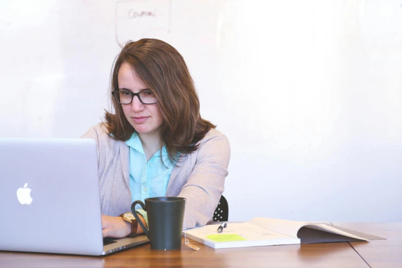 a woman sitting at a table using a laptop computer, pexels contest winner, wearing business casual dress, 9 9 designs, low quality photo, student