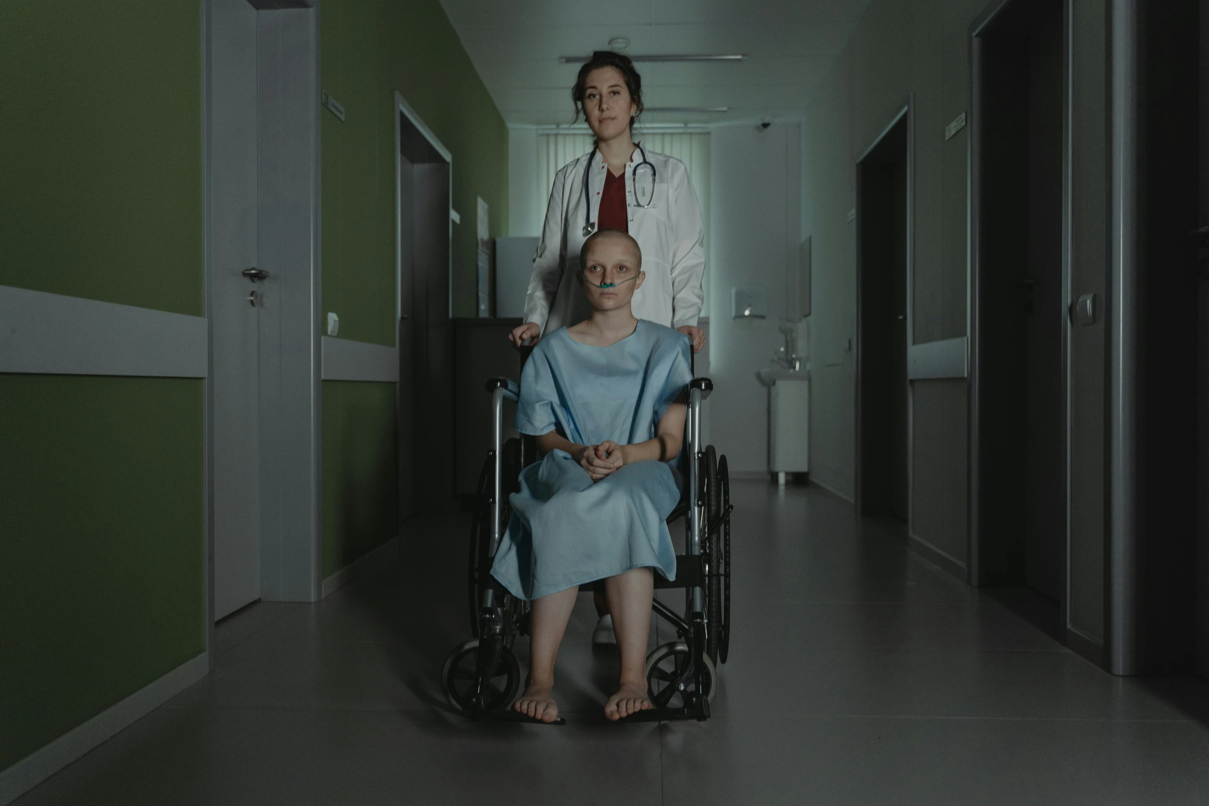 a woman pushing a man in a wheelchair down a hospital hallway, a portrait, by Adam Marczyński, hyperrealism, dramatic movie still, two women, [ theatrical ], full body 8k