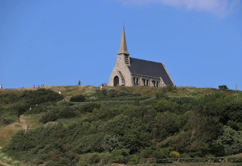 a church sitting on top of a lush green hillside, an album cover, by Antoine Verney-Carron, pexels, omaha beach, exterior view, jean francois millet, blue