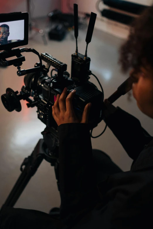 a person sitting in front of a camera on a tripod, pointing at the camera, ( ( theatrical ) ), cinematic ligting, promo image
