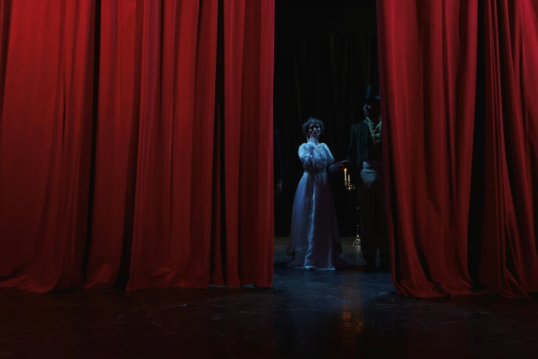 a couple of people standing in front of a red curtain, underground scene, fully covered in drapes, macabre spectacle, medium level shot