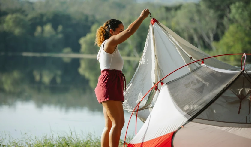 a woman setting up a tent next to a lake, fan favorite, white and red body armor, ashteroth, tent architecture