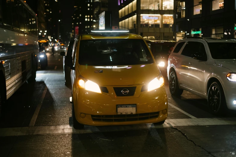 a city street filled with lots of traffic at night, taxi, with cool headlights, yellow, low-light photograph