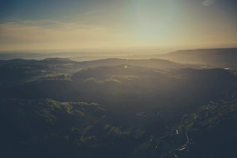 a person standing on top of a mountain at sunset, by Sebastian Spreng, pexels contest winner, happening, black forest, seen from a plane, forest plains of north yorkshire, distant village background