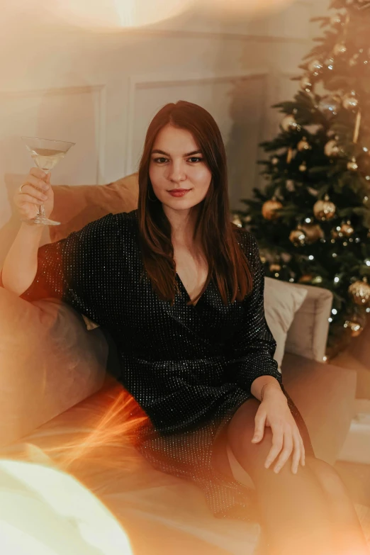 a woman sitting on a couch holding a glass of wine, a portrait, by Julia Pishtar, pexels contest winner, christmas, handsome girl, gif, multiple stories
