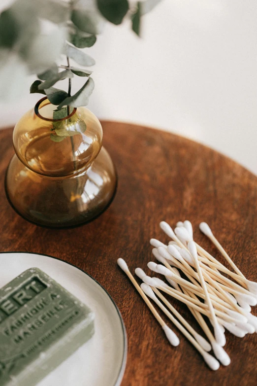 a glass vase sitting on top of a wooden table, gum tissue, candles, skincare, detail shot