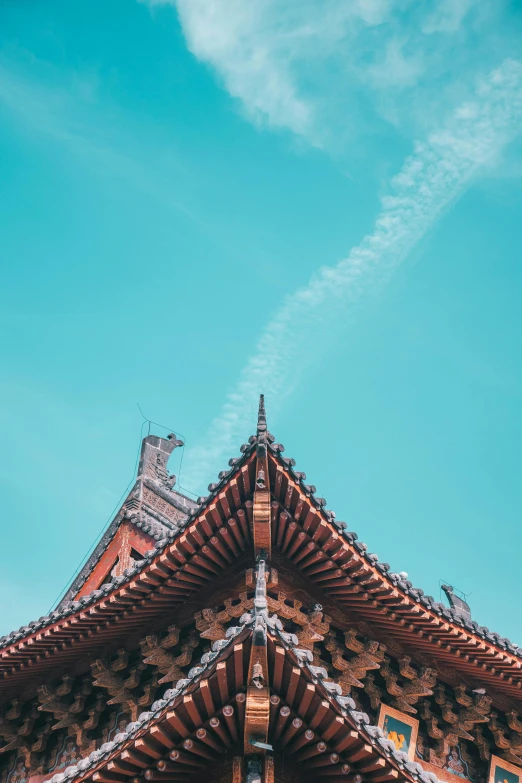 a building with a blue sky in the background, inspired by Itō Jakuchū, trending on unsplash, vietnamese temple scene, sharp roofs, square, brown and cyan color scheme