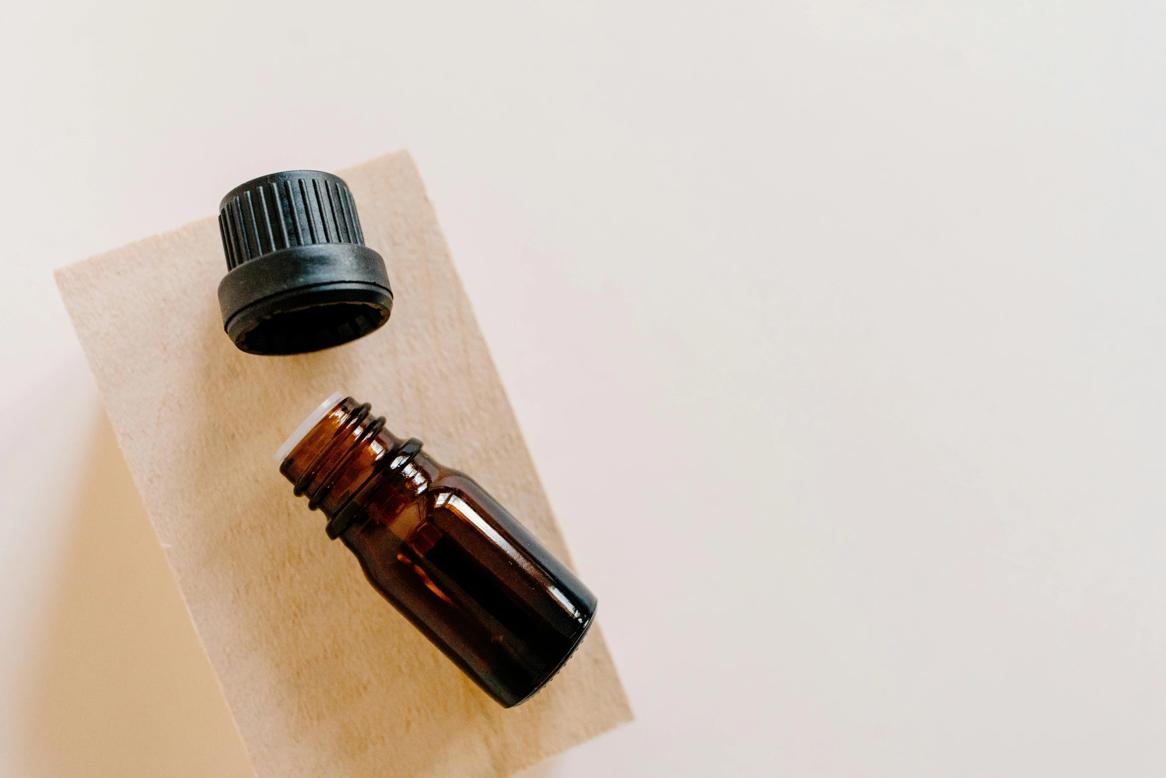 a bottle of essential oil sitting on top of a piece of paper, trending on pexels, brown, clean minimalist design, made of wood, low quality photo