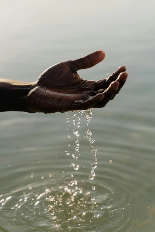 a person washing their hands in a body of water, afar, hanging, holding a holy symbol, full frame image