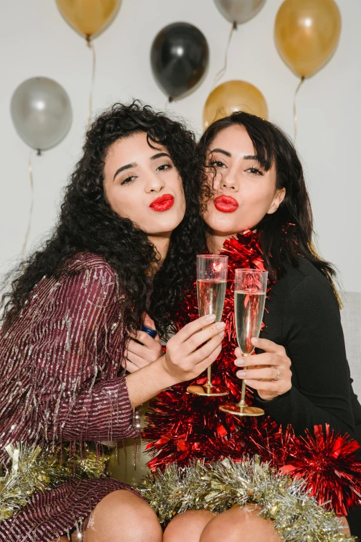 two women sitting next to each other holding champagne glasses, by Julia Pishtar, pexels, happening, both have red lips, square, wearing festive clothing, imaan hammam