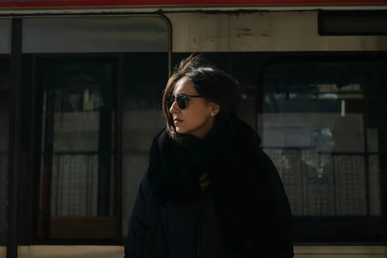 a woman standing in front of a train, pexels contest winner, wearing black coat, wearing shades, meni chatzipanagiotou, ash thorp khyzyl saleem