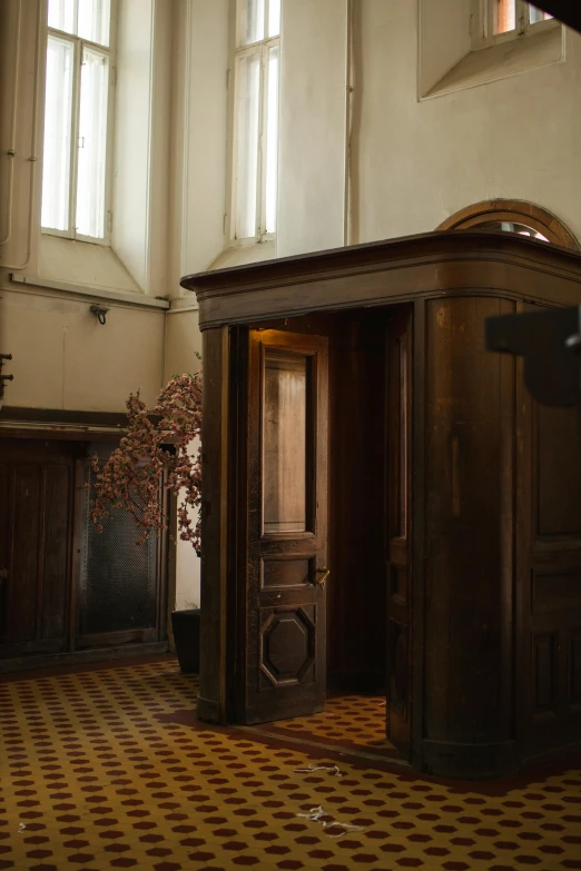 a room filled with lots of wooden furniture, inspired by Pieter de Hooch, unsplash, renaissance, elevator, in a church. medium shot, ignant, secret entrance