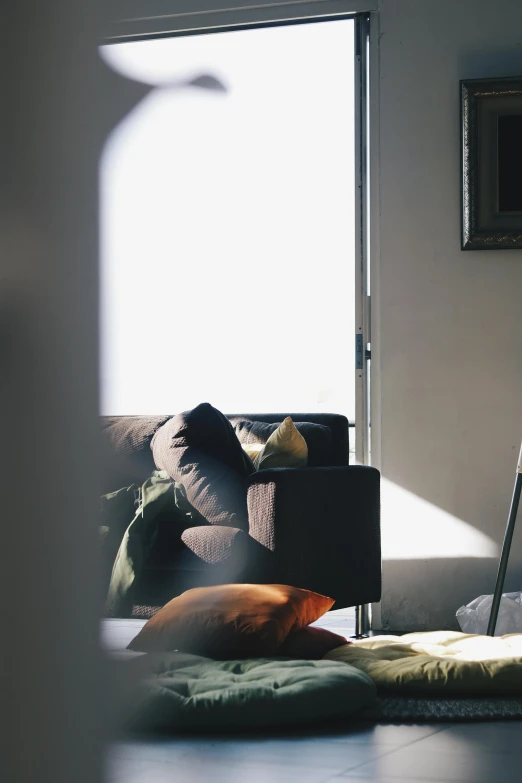 a living room filled with furniture and a window, a picture, inspired by Elsa Bleda, unsplash, frayed edges. light leaks, man sitting facing away, overexposed sunlight, medium format. soft light