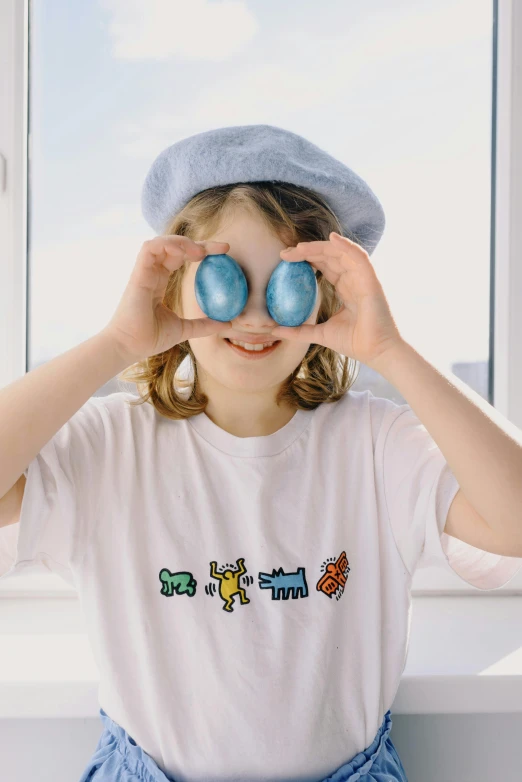 a little girl that is sitting on a window sill, a child's drawing, inspired by Damien Hirst, graffiti, wearing sunglasses and a cap, printed on a cream linen t-shirt, translucent eggs, wearing a light blue shirt