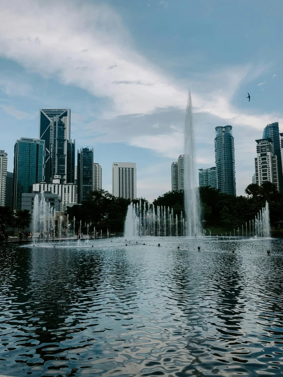 a large body of water with a bunch of buildings in the background, by Cherryl Fountain, pexels contest winner, hurufiyya, malaysian, in a city park, immortality fountain, snapchat photo