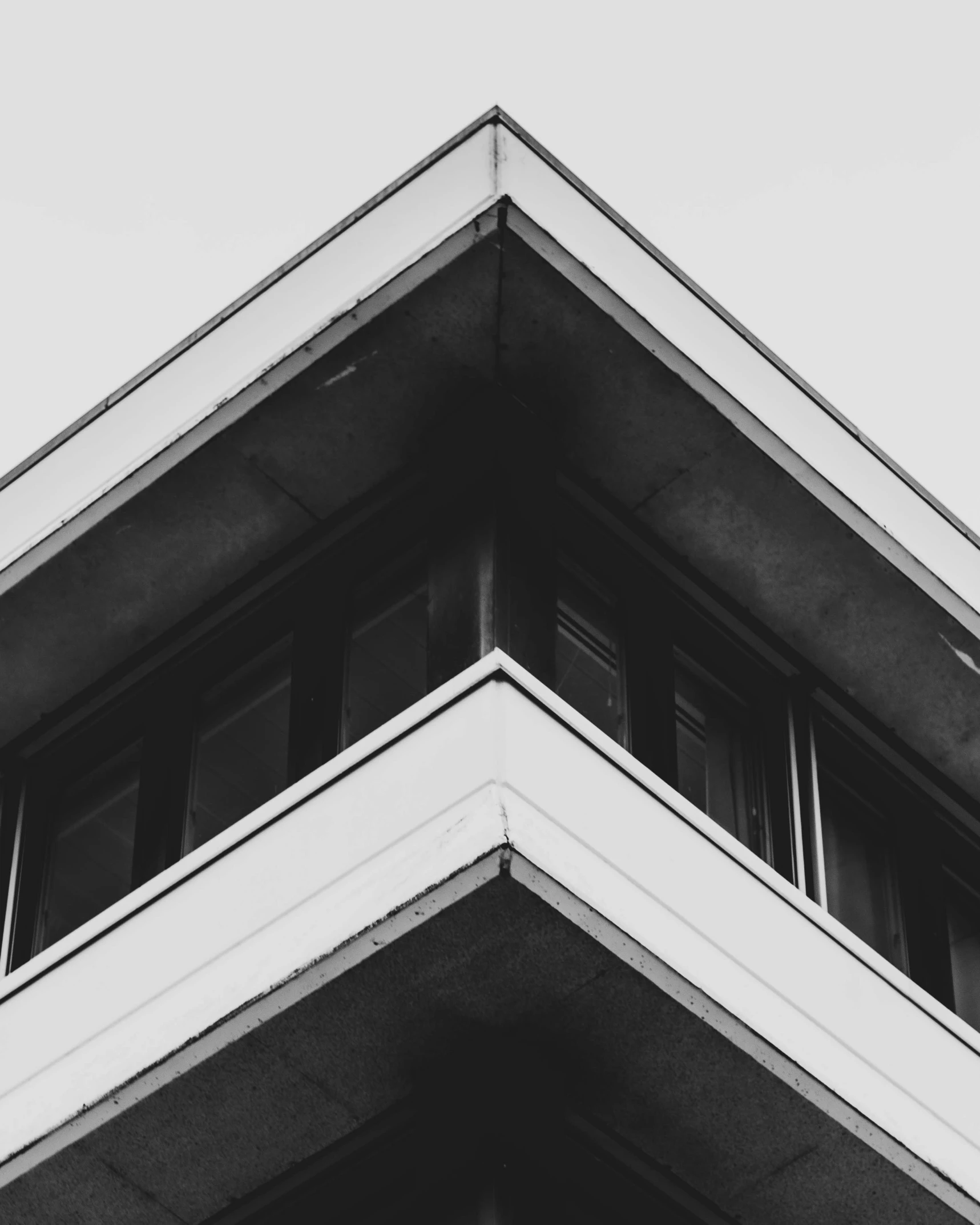 a black and white photo of a tall building, inspired by Bauhaus, unsplash, brutalism, concrete balcony, instagram post, corner, profile image