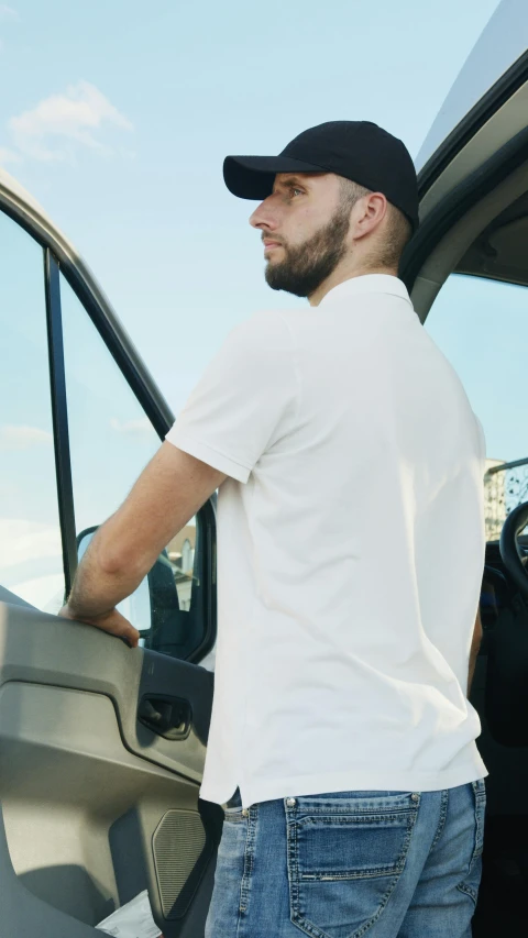 a man standing in the driver's seat of a van, plain white tshirt, digital image, focused photo