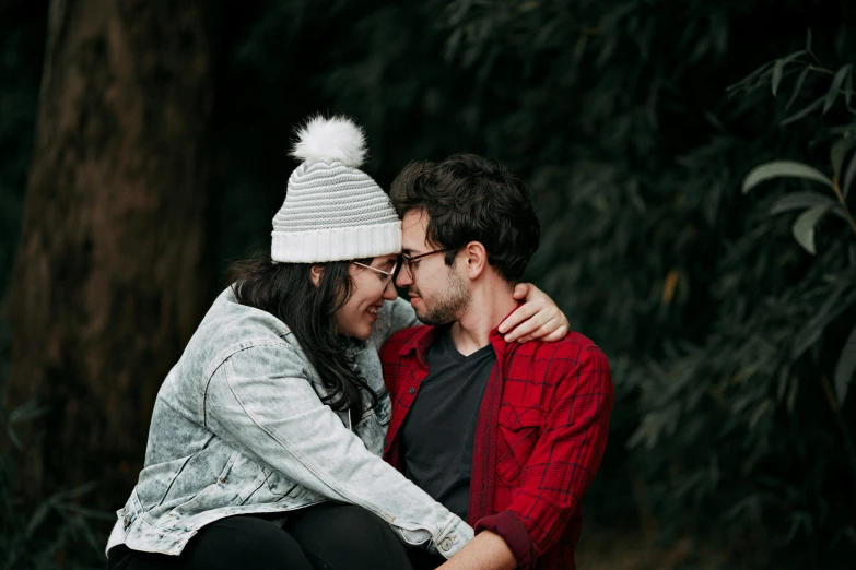a man and a woman sitting next to each other, by Lucia Peka, pexels contest winner, beanie, holding each other, sydney hanson, background image