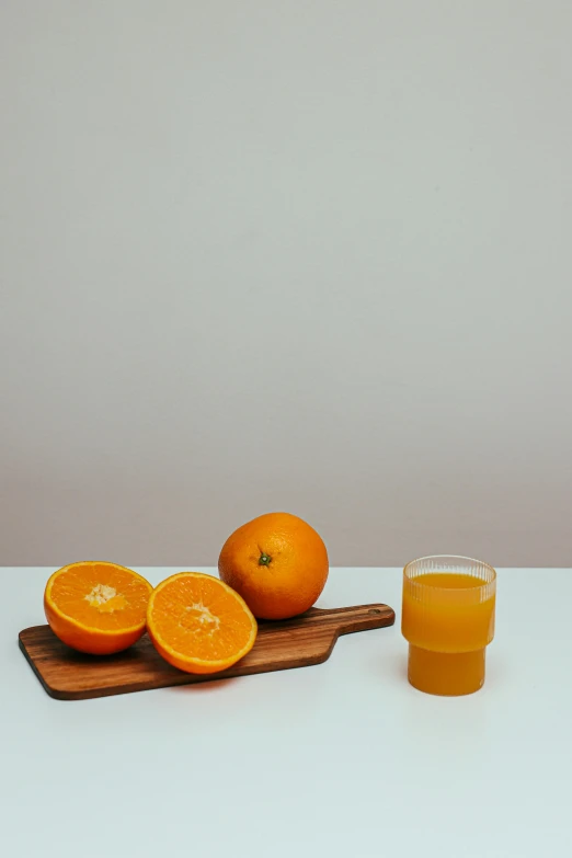 an orange sitting on top of a cutting board next to a glass of orange juice, pexels, on a gray background, uncrop, high quality photo, transparent background