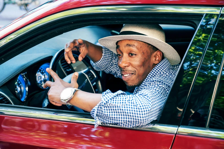 a man sitting in the driver's seat of a red car, inspired by Richmond Barthé, with eddie murphy, gilleard james, tipping his fedora, family friendly