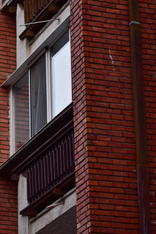 a clock that is on the side of a building, red bricks, near a window, up-close, worst place to live in europe