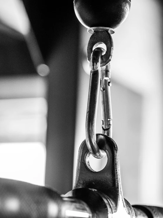 a close up of a handle on a bike, by Adam Marczyński, chains hanging from ceiling, background a gym, black-and-white, hook as ring