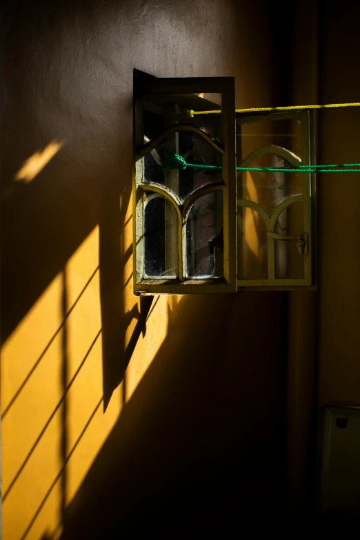 a light shines through a window in a dark room, a picture, inspired by Elsa Bleda, yellow windows and details, long cast shadows, yellow and green, taken in the early 2020s