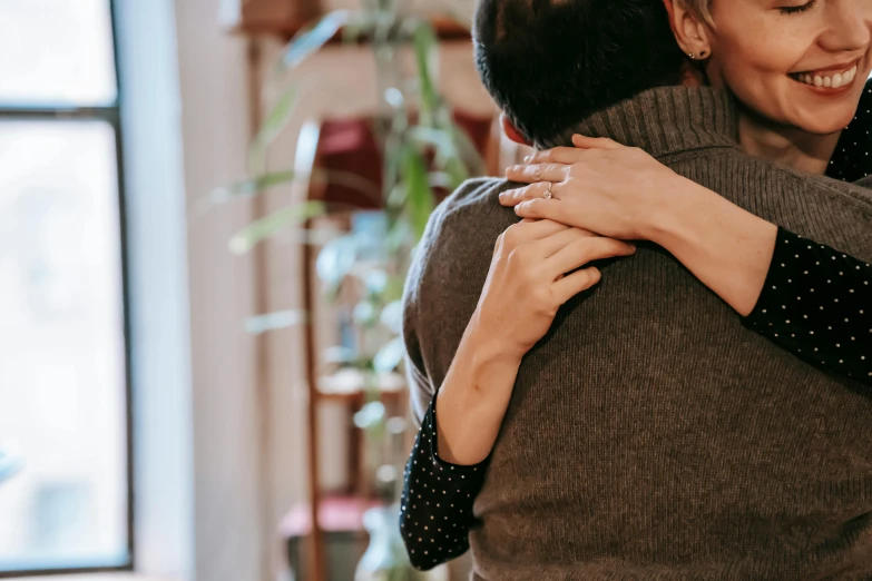 a couple of people that are hugging each other, trending on pexels, background image, indoor scene, his arms are behind his back, multiple stories