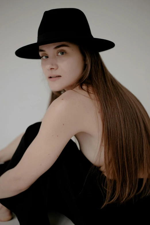 a woman with long hair wearing a black hat, non binary model, flat chested, over-shoulder shot, hair : long brown