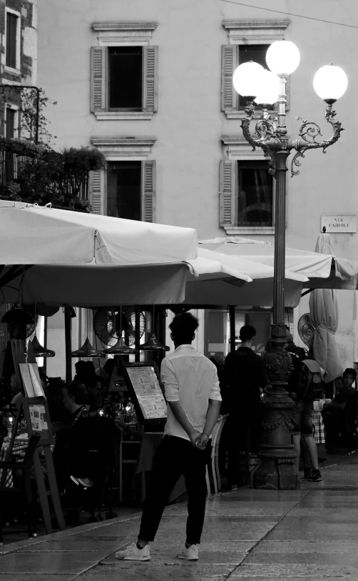 a black and white photo of people walking down a sidewalk, a black and white photo, by Giovanni Pelliccioli, renaissance, some stalls, late summer evening, trading art station, nice