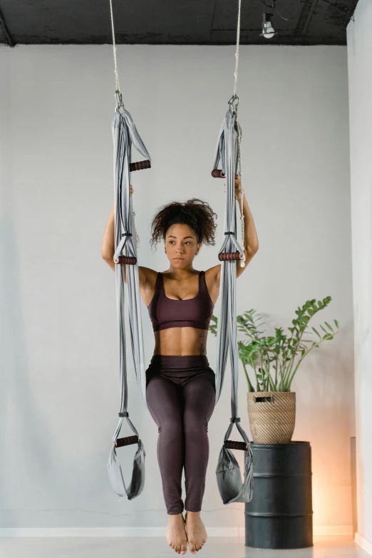 a woman is hanging upside down on a hammock, by Jan Tengnagel, arabesque, model is wearing techtical vest, gray canvas, local gym, wētā fx