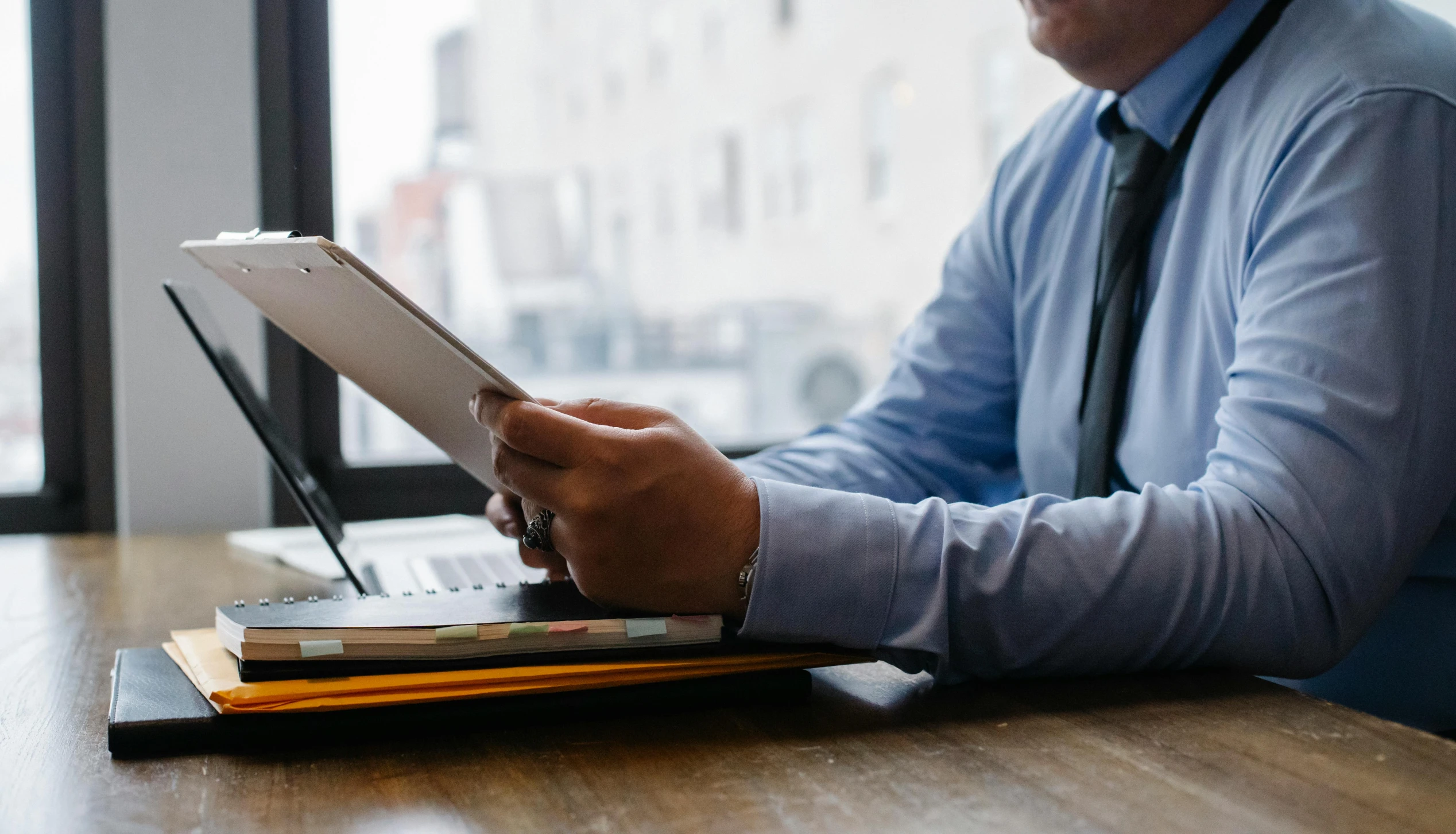 a man sitting at a table using a laptop computer, by Carey Morris, pexels contest winner, holding a clipboard, lawyer, lachlan bailey, no - text no - logo