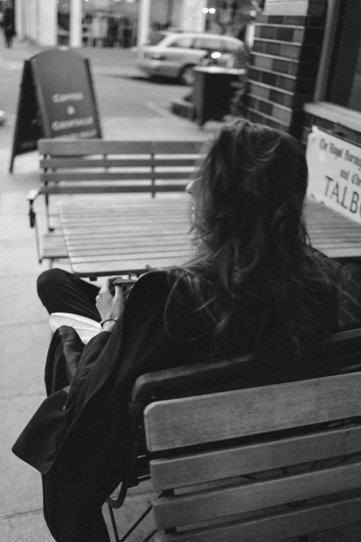 a black and white photo of a woman sitting on a bench, unsplash, realism, from the back, young with long hair, in a sidewalk cafe, 15081959 21121991 01012000 4k