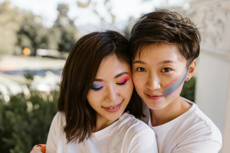 a couple of women standing next to each other, a picture, trending on pexels, rainbow accents, young cute wan asian face, gay rights, face painting