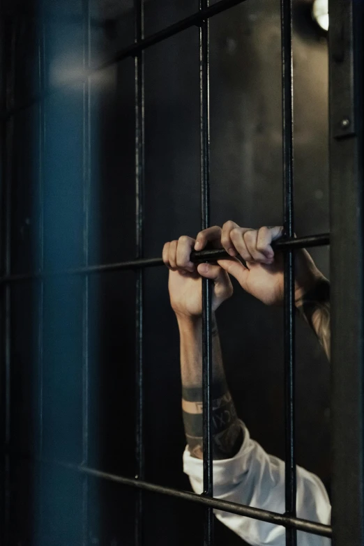 a man is looking through the bars of a jail cell, trending on pexels, tattooed, holding a staff, color footage, hands up