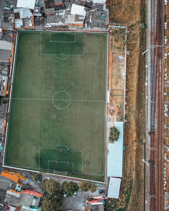 an aerial view of a soccer field surrounded by buildings, unsplash contest winner, conceptual art, brown, low quality photo, multiple stories, colombia