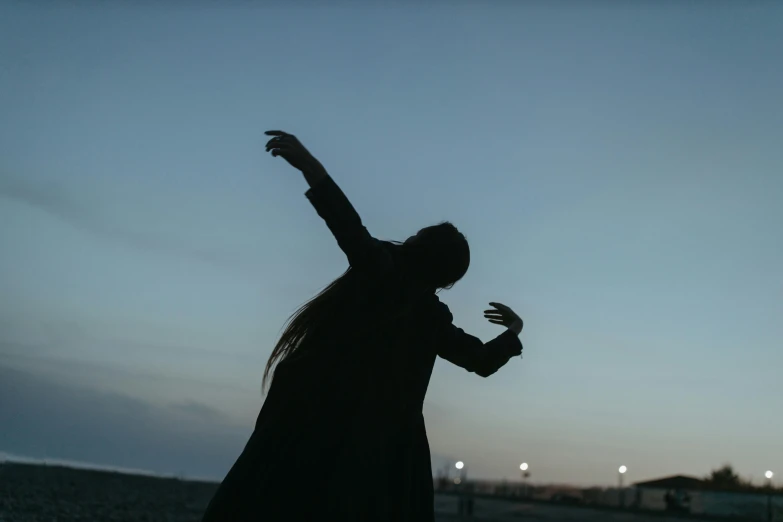 a silhouette of a woman throwing a frisbee, an album cover, unsplash, woman in black robes, dusk, ignant, goth people dancing