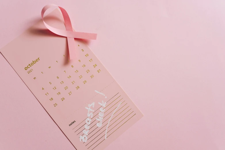 a pink calendar with a pink ribbon on it, by Julia Pishtar, pexels contest winner, essence, medical, 5 k, pink skin