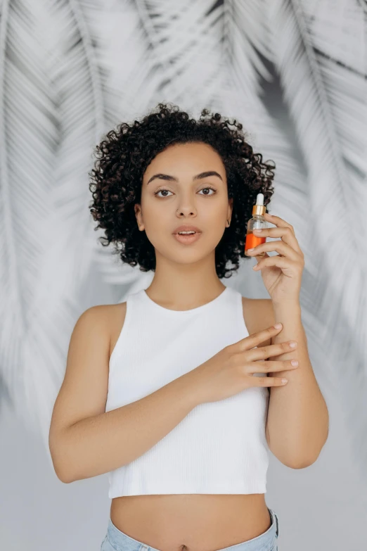 a woman standing in front of a palm tree holding an orange, trending on pexels, renaissance, hair fluid, mixed race, on a gray background, carrying a bottle of perfume