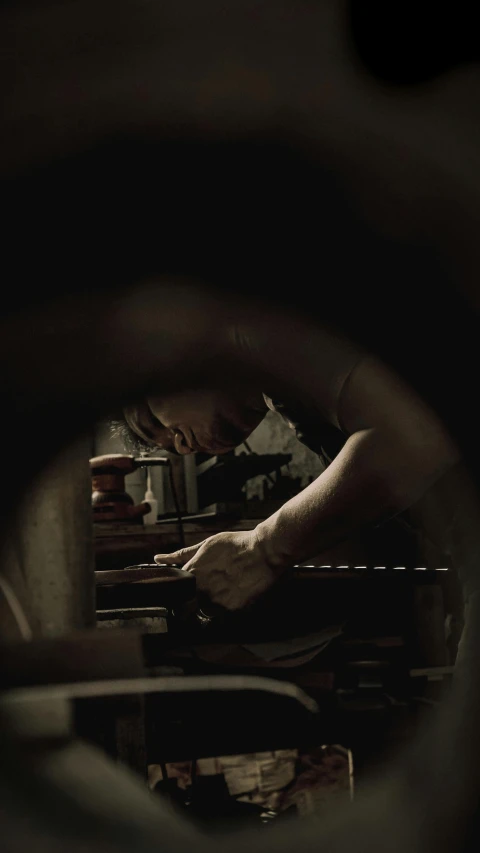 a close up of a person working on a machine, an album cover, inspired by Roy DeCarava, pexels contest winner, renaissance, gunsmithing, dark tone, ( ( theatrical ) ), woodturning