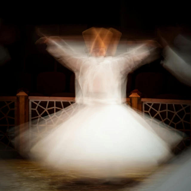 a blurry photo of a woman in a white dress, a hologram, by Ibrahim Kodra, pexels contest winner, arabesque, sufism, he is dancing, ( ( theatrical ) ), slide show
