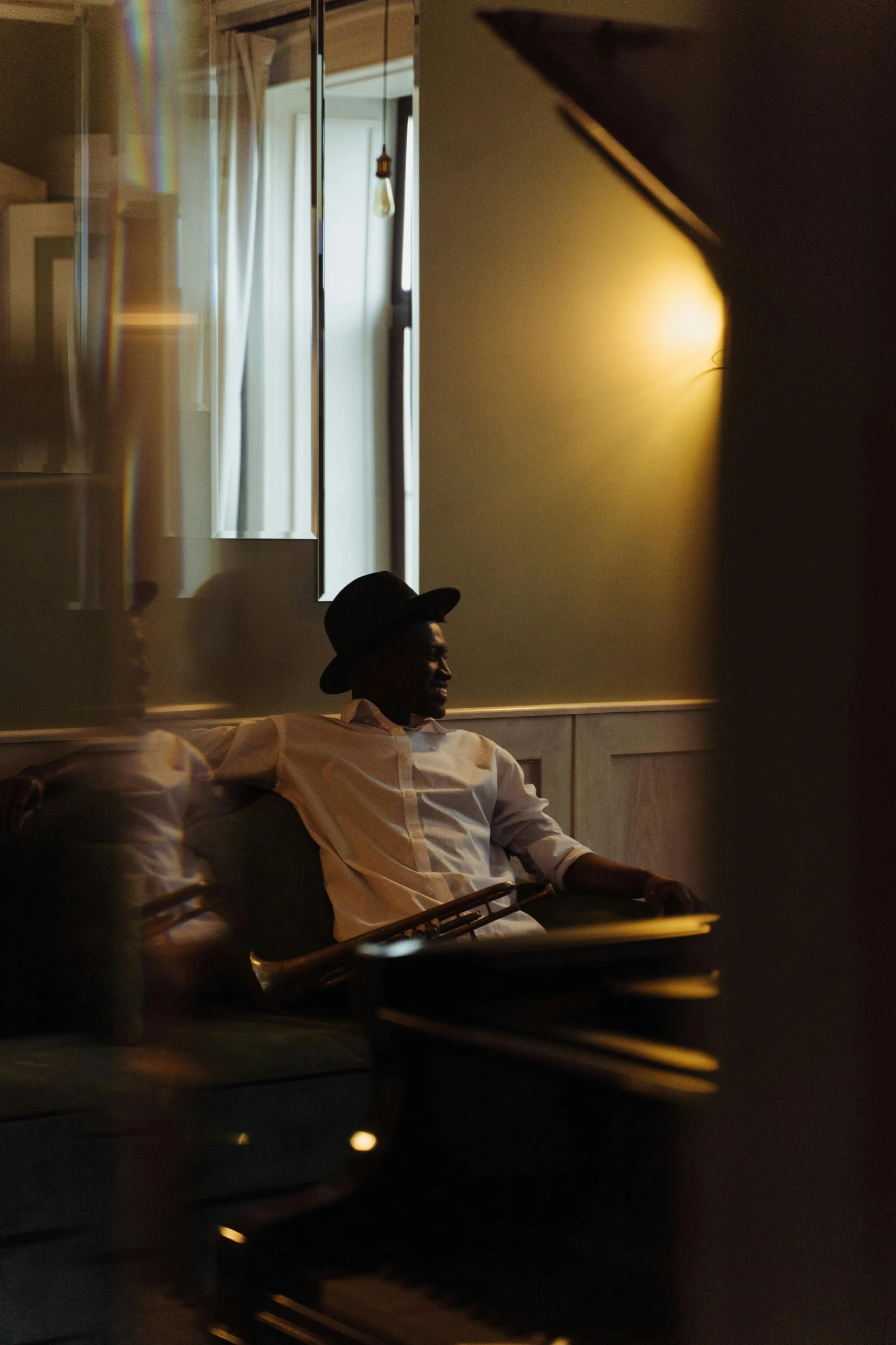 a man sitting on a couch in a living room, an album cover, inspired by Gordon Parks, pexels contest winner, hotel room, side light, black man, evening lighting