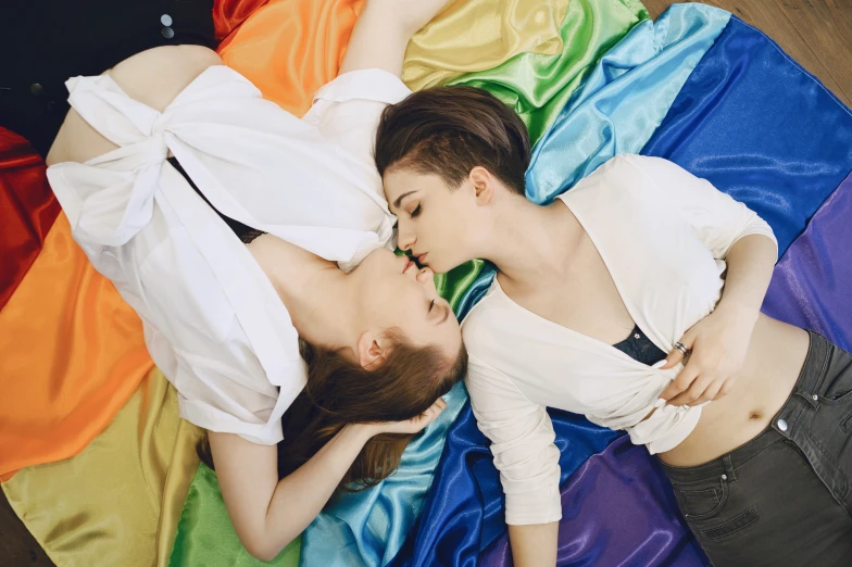 a couple of women laying on top of each other, trending on unsplash, bauhaus, lgbt flag, dilraba dilmurat, romantic lead, maia sandu hyperrealistic