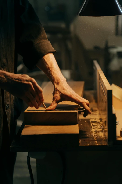 a man is working on a piece of wood, by David Simpson, pexels contest winner, arts and crafts movement, shot from cinematic, thumbnail, australian, dimly lit scene