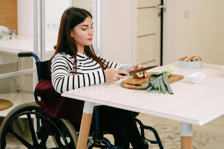 a woman in a wheel chair cutting a sandwich, by Julia Pishtar, trending on pexels, hurufiyya, sitting on a desk, avatar image