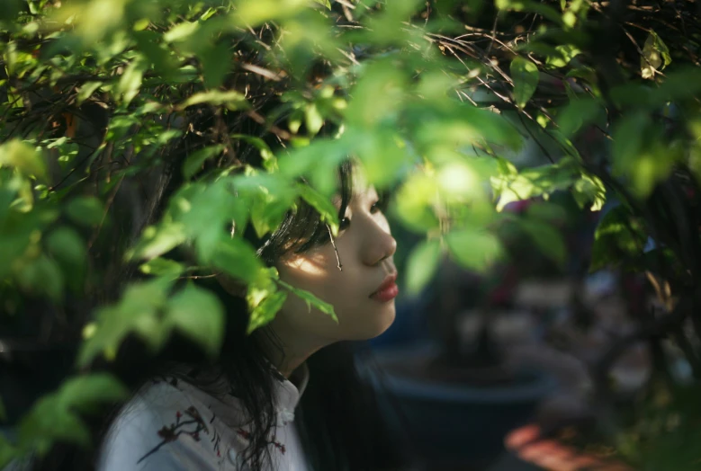 a woman standing under a tree with her eyes closed, a picture, unsplash, realism, jinyoung shin, green foliage, close up portrait photo, shot on hasselblad